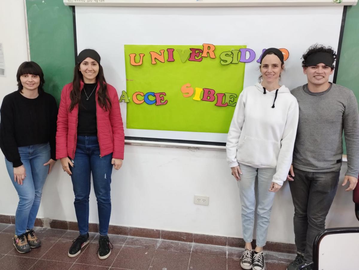  Estudiantes  junto al afiche con la frase terminada " Universidad accesible"