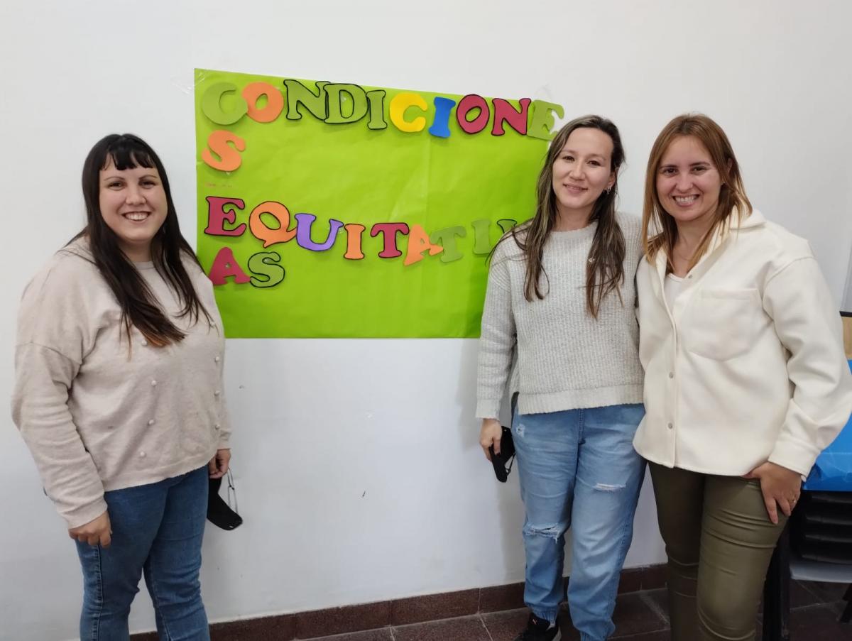  Estudiantes  junto al afiche con la frase terminada " Condiciones equitativas"